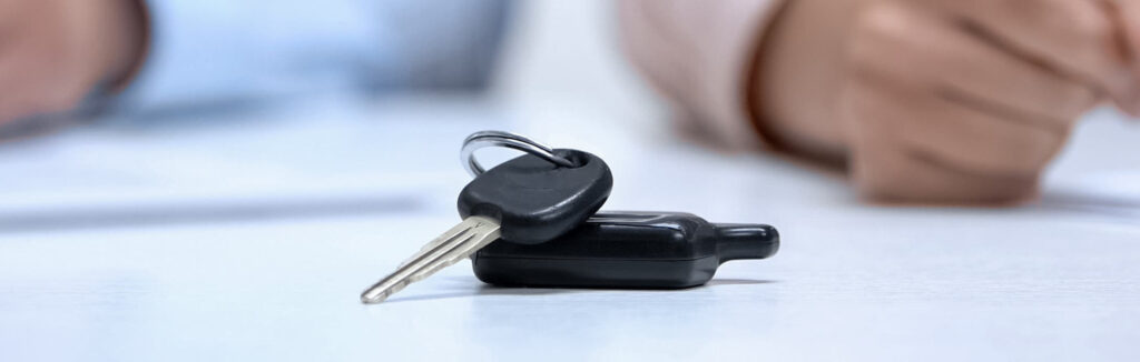 Car keys with couple signing documents in the background. Symbolic of property settlement after separation